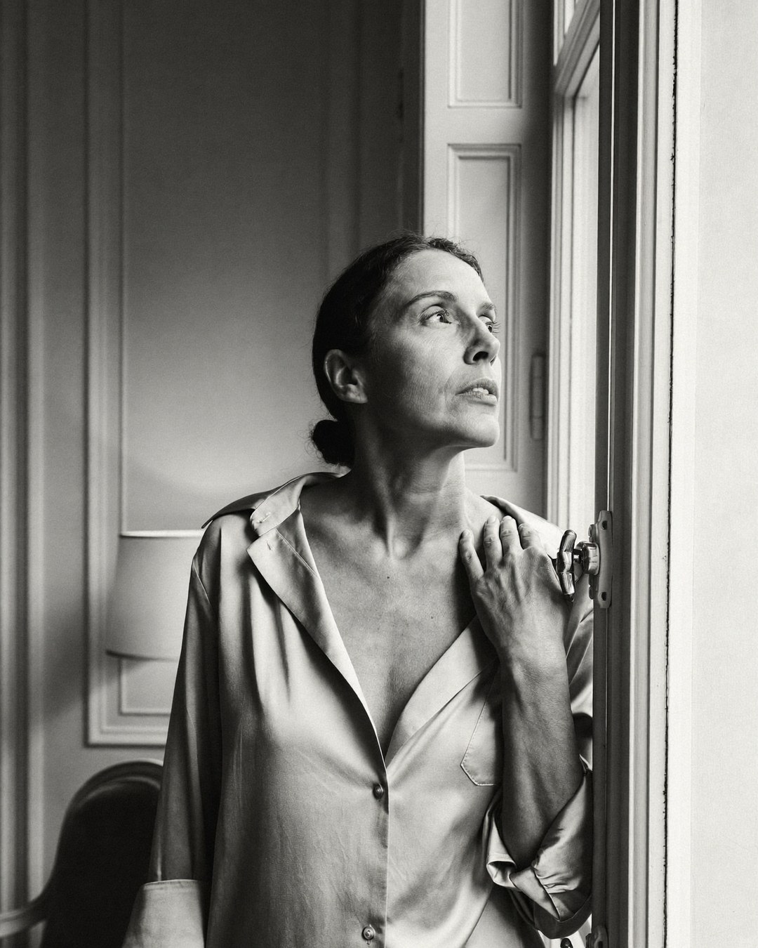 An elegant woman considering a face and neck lift by a window